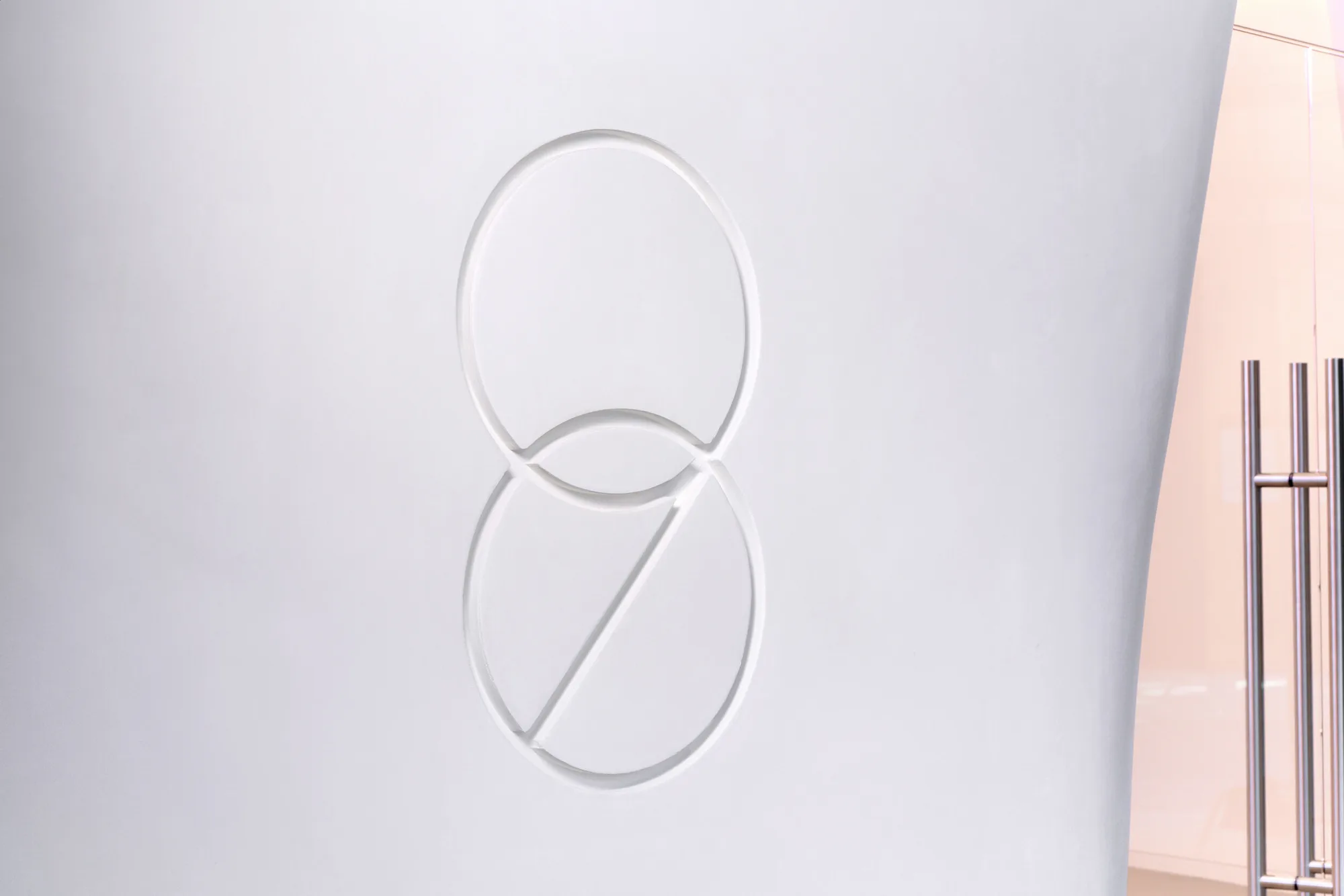 The Room 98 mark in relief on a white wall beside a glass door.