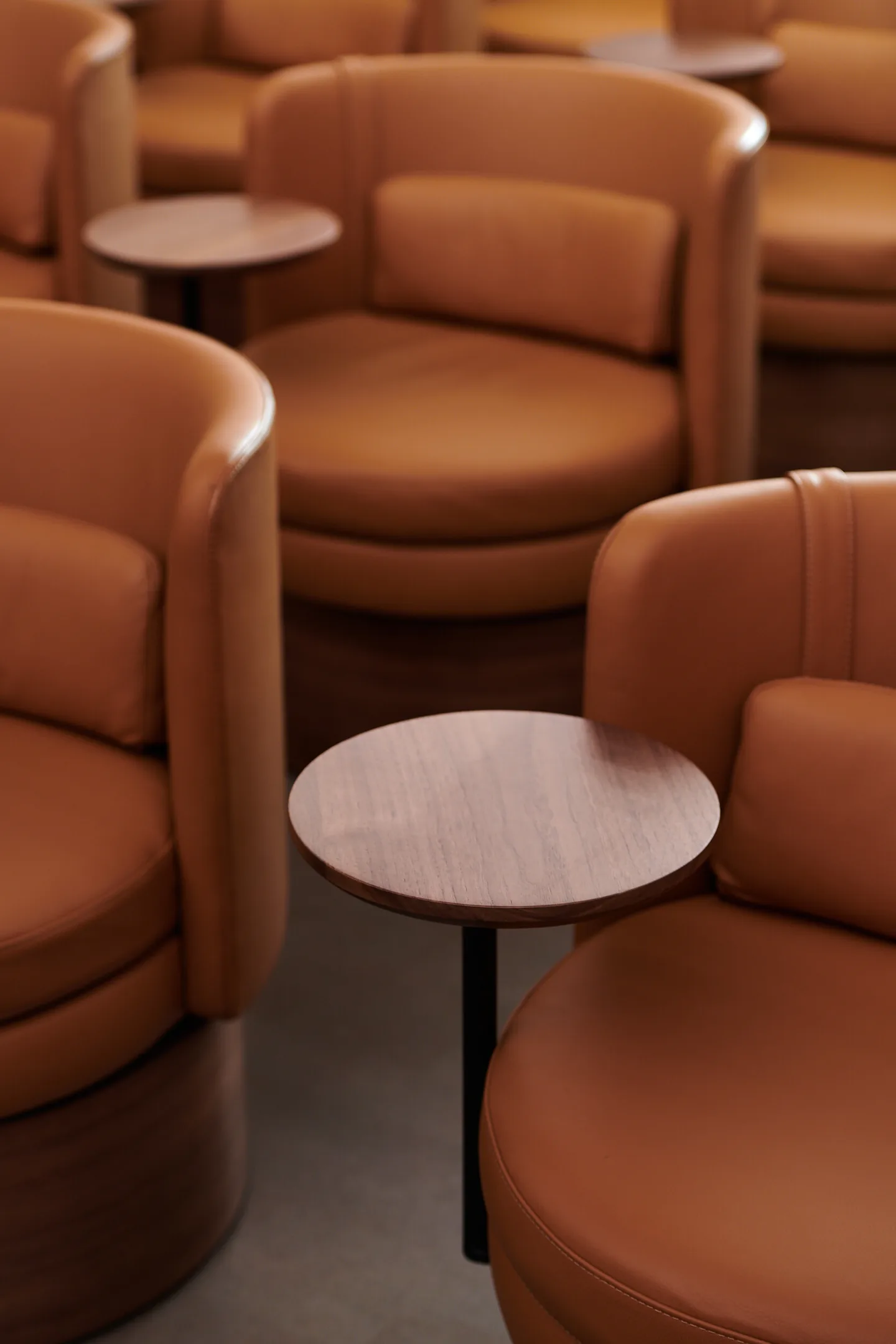 Tan leather swivel chairs with small side tables.