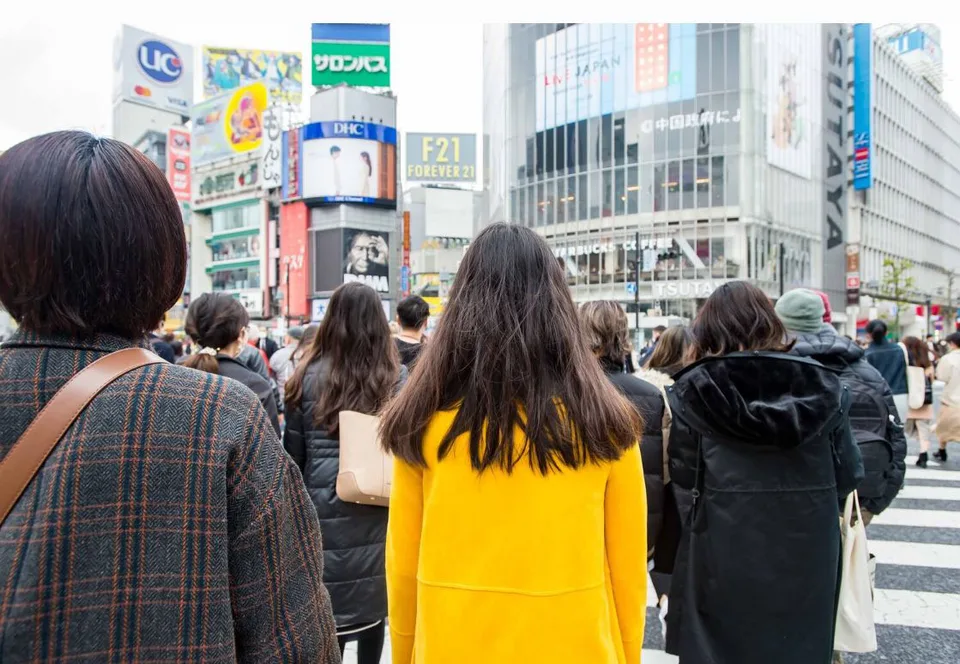 People crossing a busy Tokyo street with bright signage.