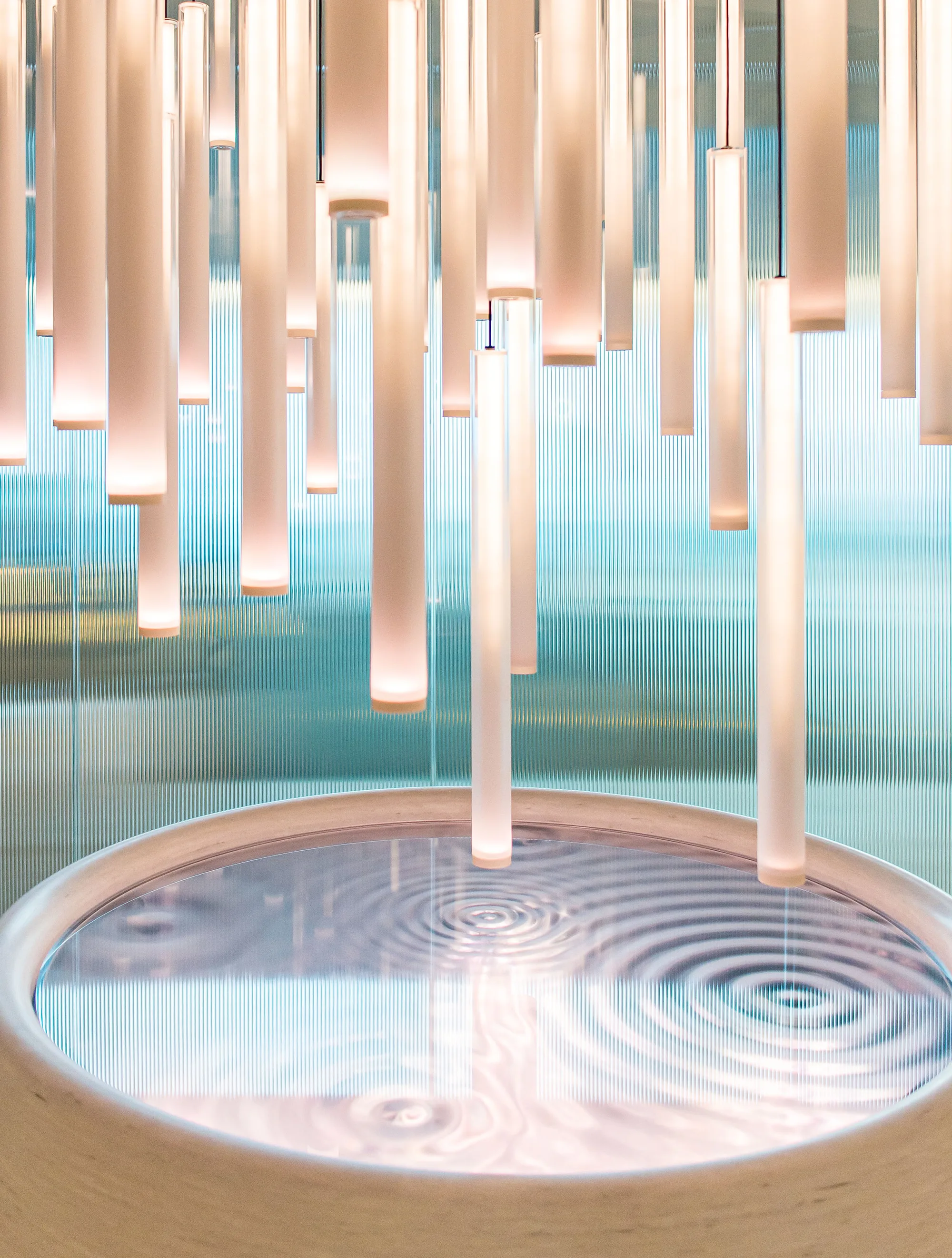 Close view of a shallow round basin with concentric ripples under hanging white tubes.