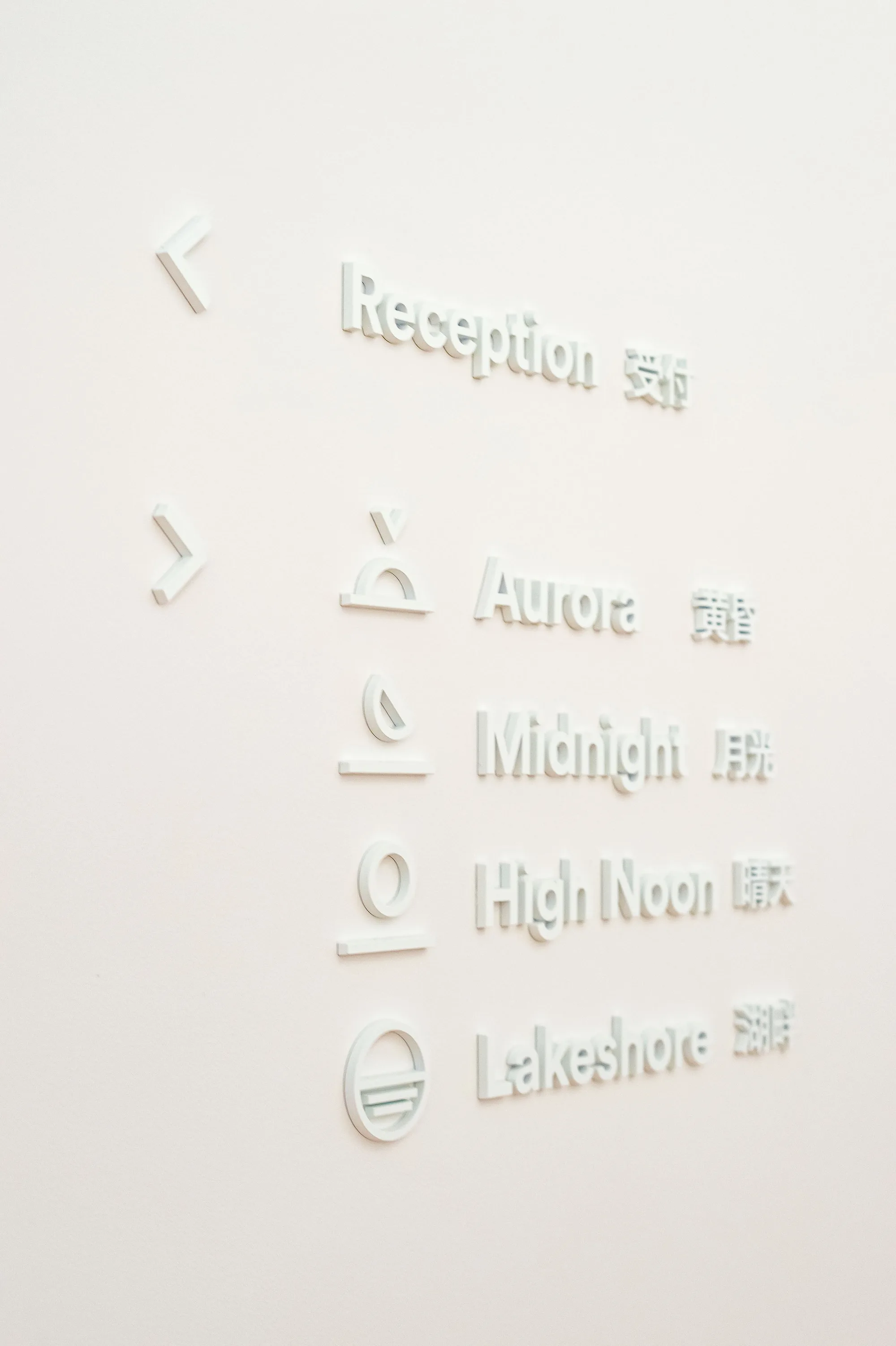 White wall with raised lettering and icons listing room names in English and Japanese.