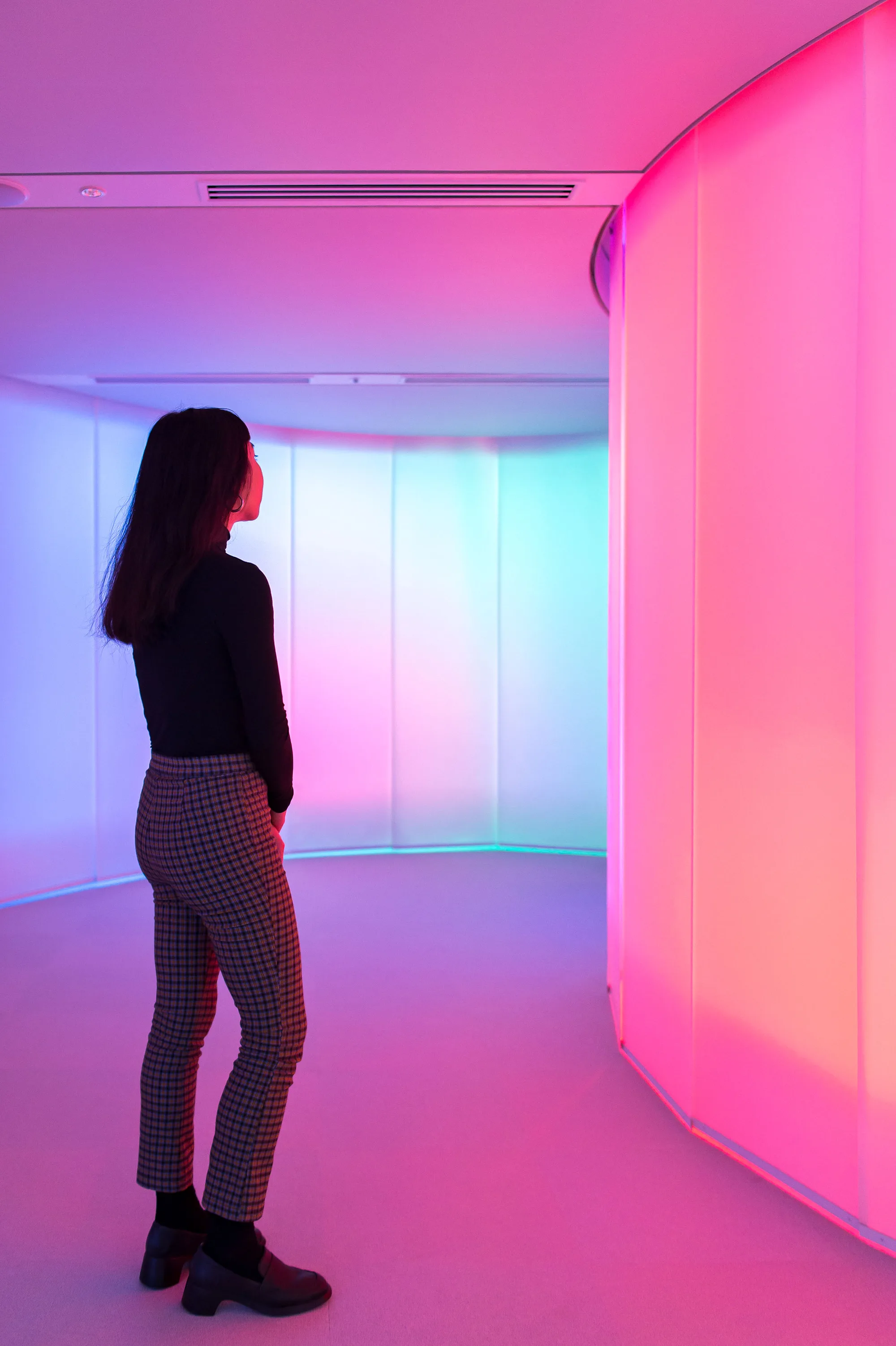 A person standing in a room lit in pink and blue gradients.