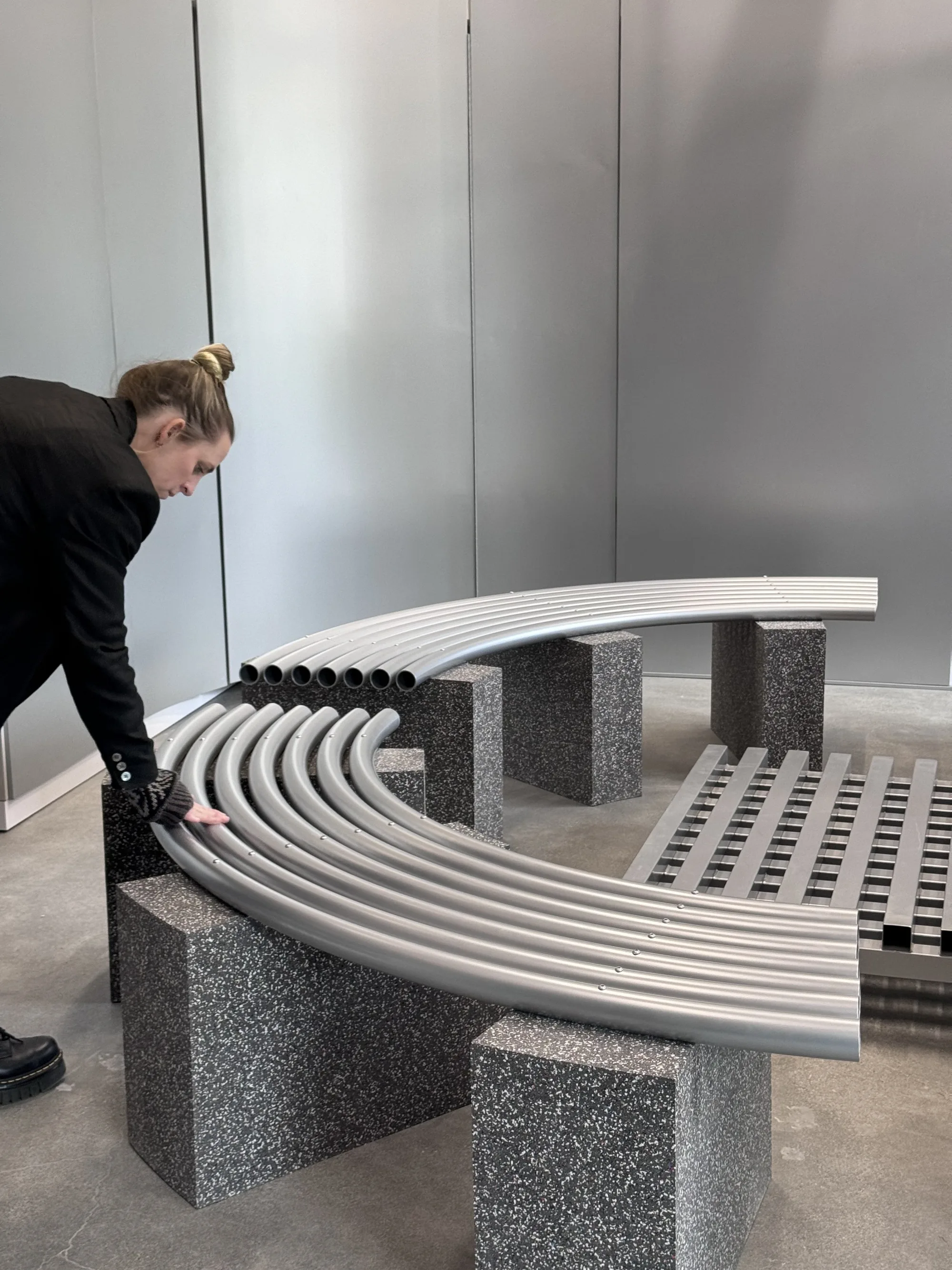 A person adjusting the curved tube bench on stone supports in the finished store.