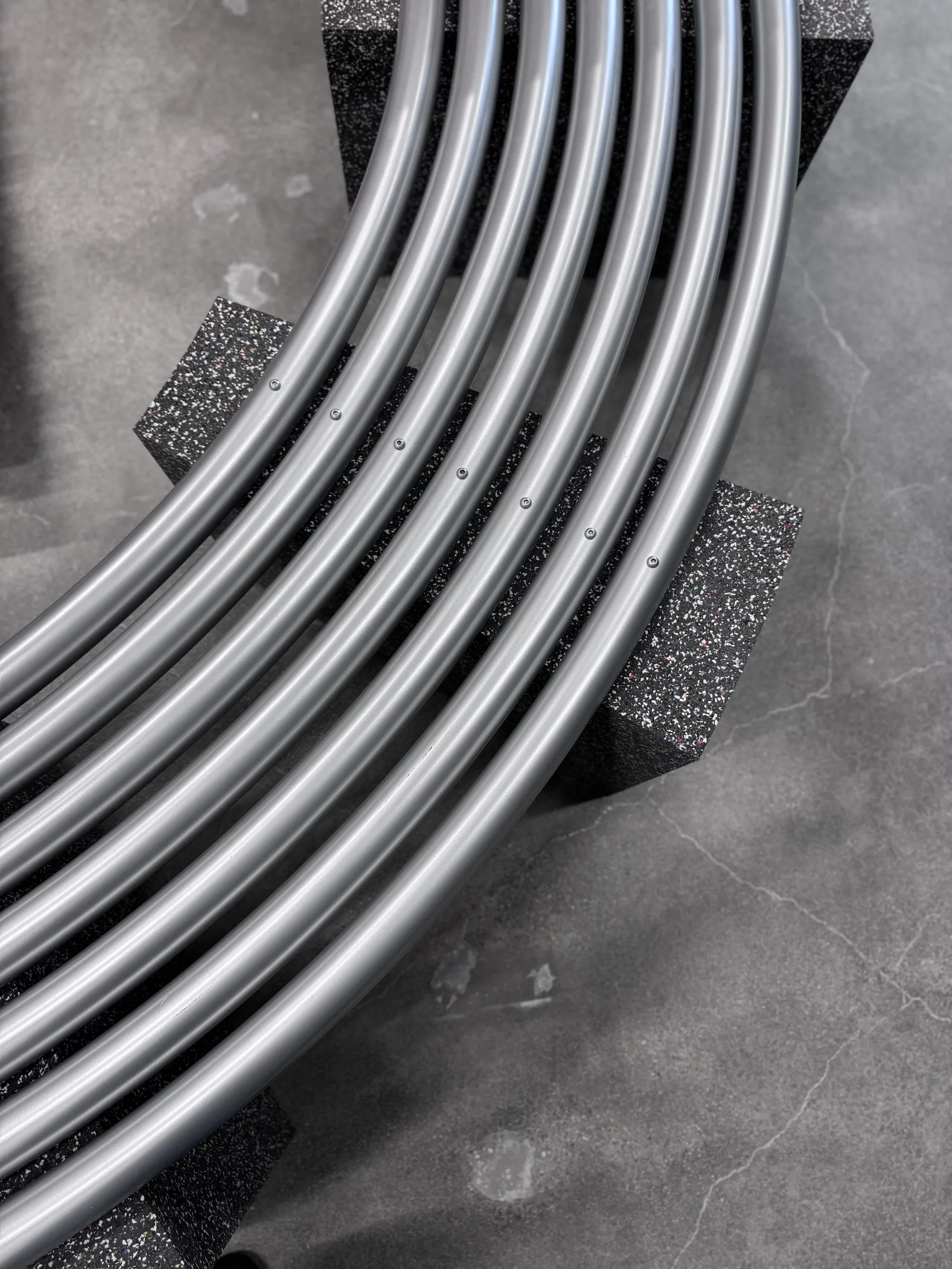 Close view of parallel curved metal tubes resting on a speckled stone block.