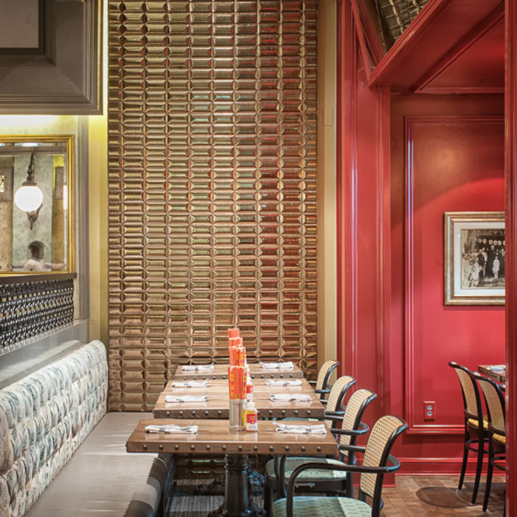 Table beside a patterned banquette, with a tall wall of timber tiles and red panelling.