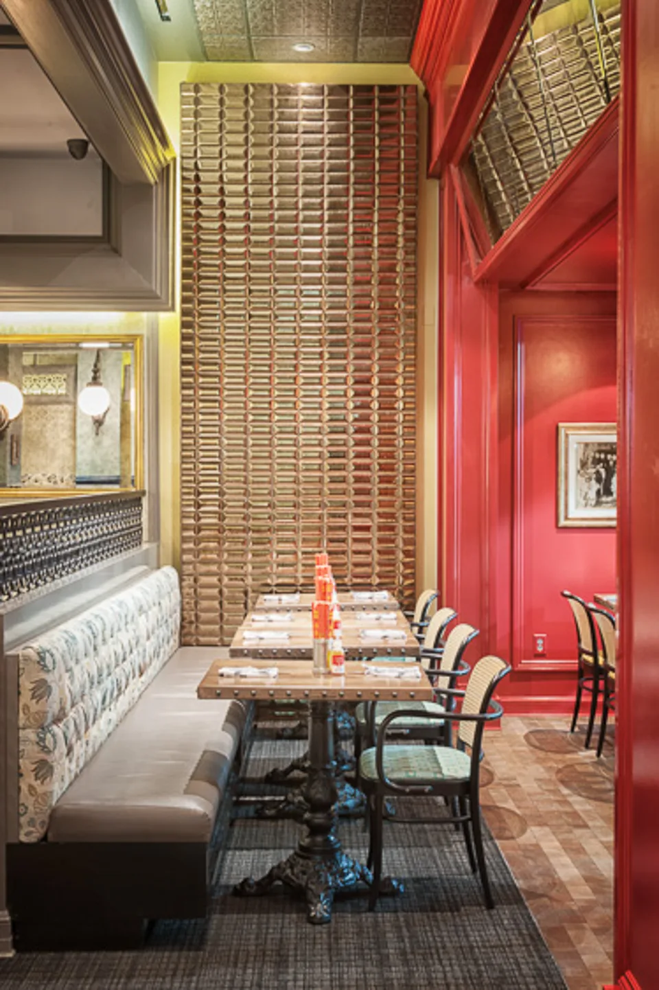 Tall view of a wall of timber tiles above a long banquette and a row of set tables.