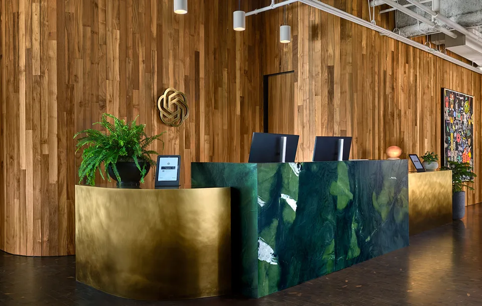 Bellevue reception desk in brass and green stone against a timber wall.