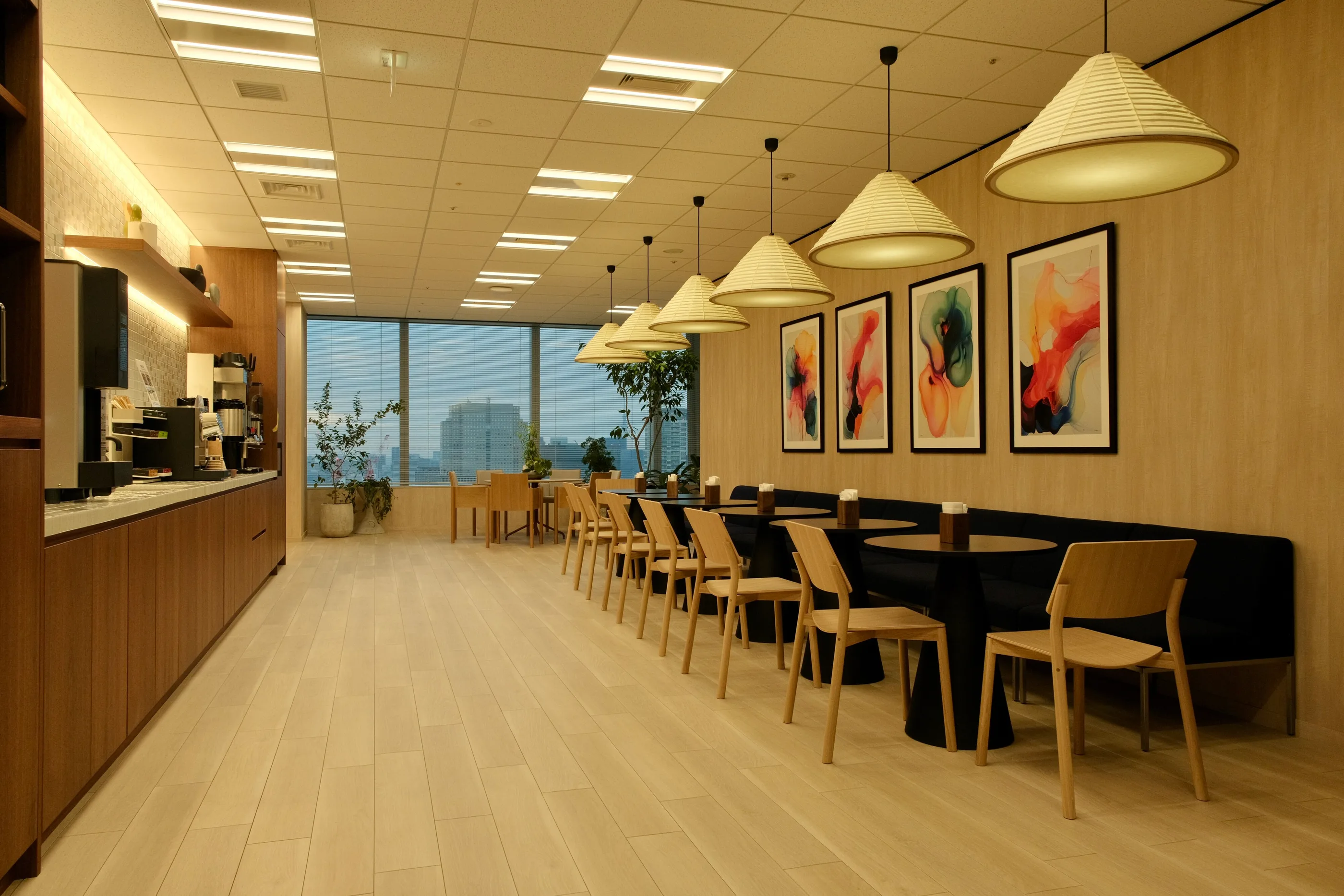 A long counter with stools, pendant lights and a view of the city.