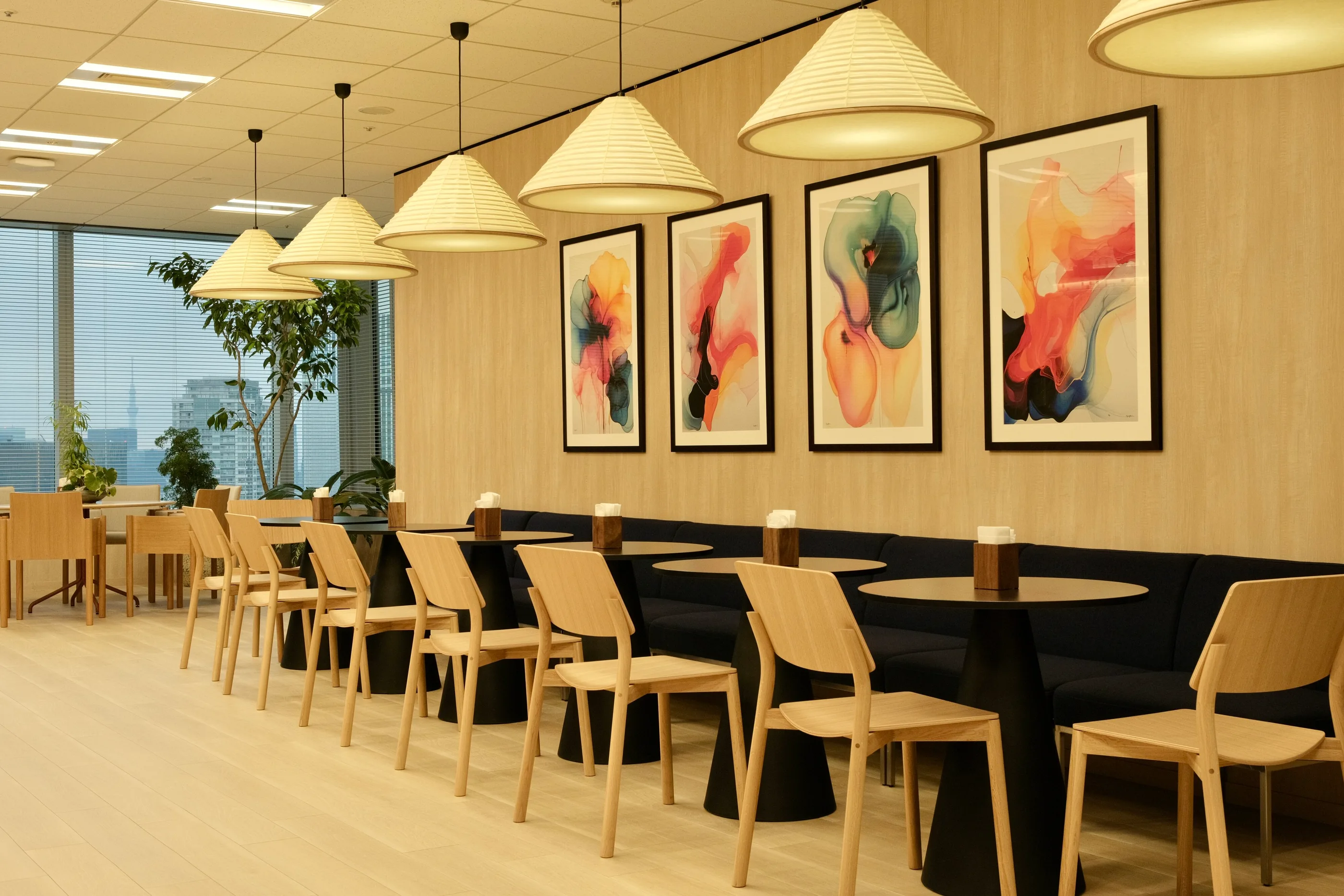 Row of stools at a counter beneath cone pendant lights and framed artworks.