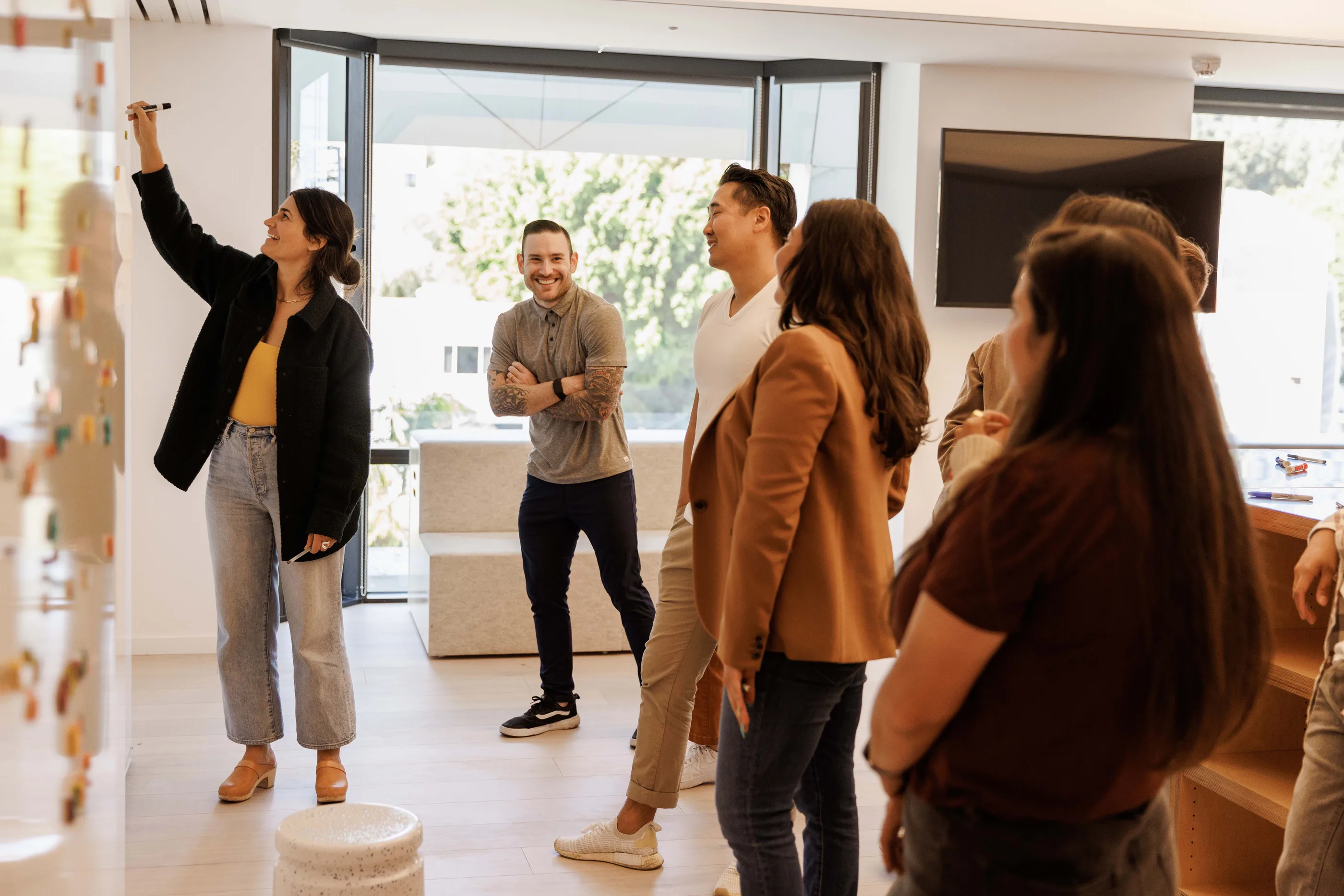 Five people standing and talking, one reaching to pin an item on a hanging display.